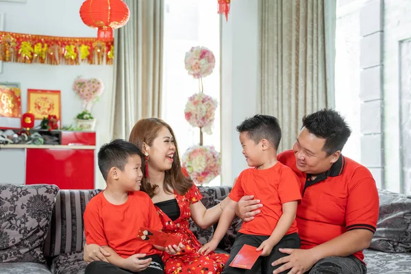 Asian chinese family with two son holding ang pao when chatting together