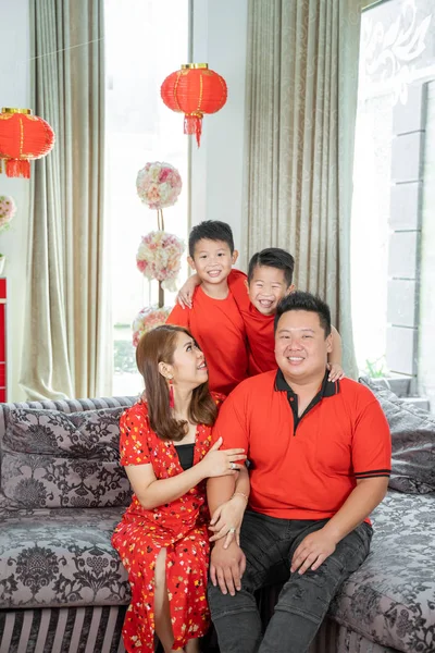 Asian chinese family with two son holding ang pao smiling when sitting on sofa