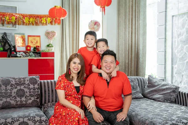Asian family with two son holding ang pao smiling looking at camera