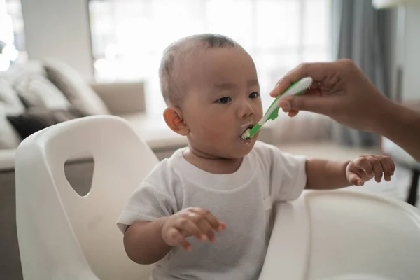 Asiático madre alimentación su bebé hijo con cuchara —  Fotos de Stock