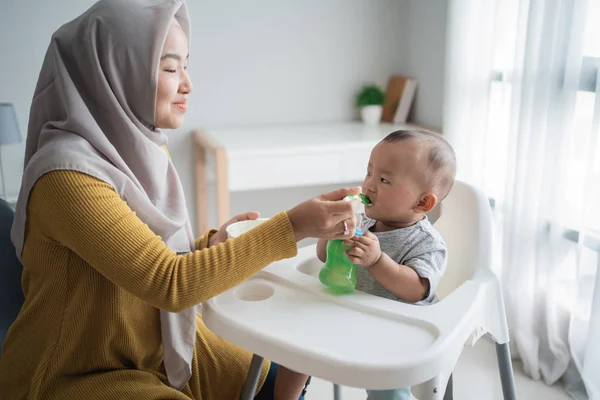 Mother feeding her baby boy while sitting on high chair — Stock Photo, Image