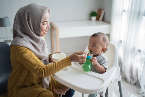 Asian Mother feeding her baby son with spoon — Stock Photo, Image