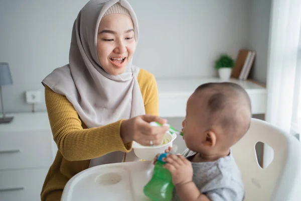 Mother feeding her baby boy while sitting on high chair — 스톡 사진