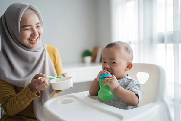 Азиатская мать кормит своего маленького сына ложкой — стоковое фото