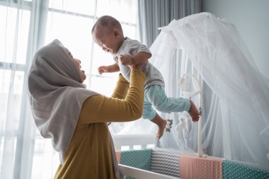 Asyalı anne bebeğini taşıyor.