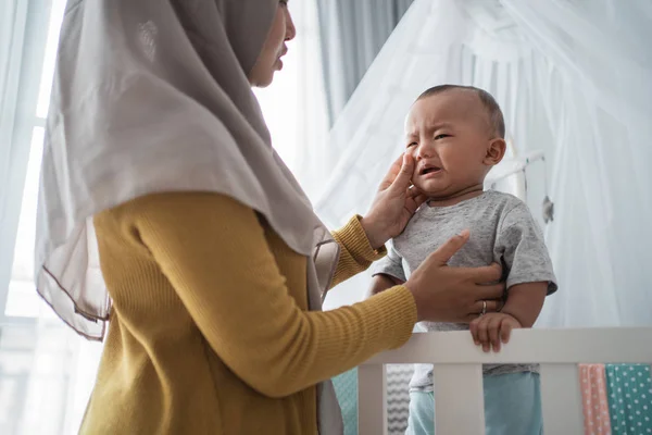 Mother try to comfort her cry child at the crib — Stock Photo, Image