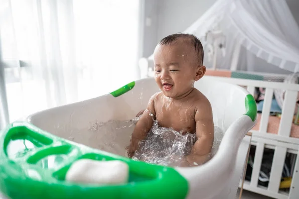 Niño pequeño disfrutar jugar con el agua mientras toma un baño —  Fotos de Stock