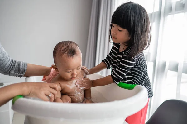 Helpful sister wash her baby brother during bath time — Stock Photo, Image