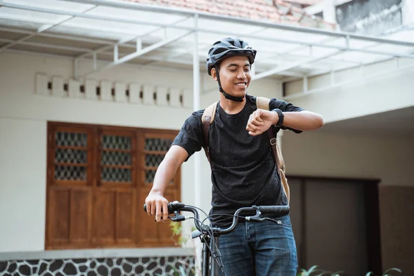 Asiatico giovane uomo in piedi con pieghevole bicicletta mentre cercando il suo orologio — Foto Stock