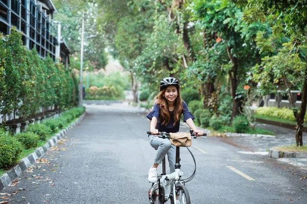 Asiatique jeune femme va porter un casque et un sac à cheval son vélo pliant — Photo