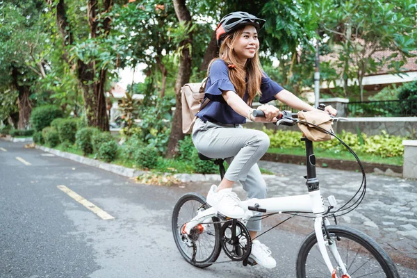 Asiatique jeune femme va porter un casque et un sac à cheval son vélo pliant — Photo