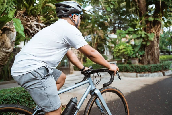 Asiático joven hombre usando cascos de bicicleta al montar en bicicleta — Foto de Stock