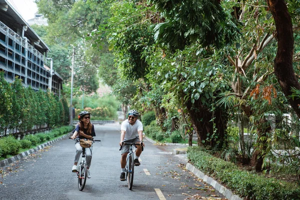 Parejas jóvenes que usan cascos disfrutan montando bicicletas juntos —  Fotos de Stock