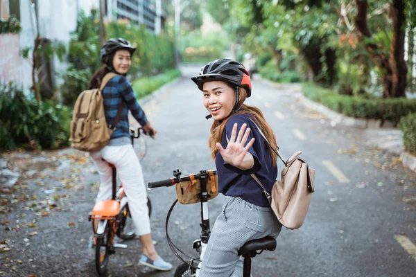 Dos mujeres jóvenes está listo para ir en bicicleta plegable y mira hacia atrás con cinco altos —  Fotos de Stock