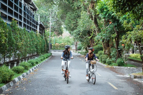 Dois ásia mulher vestindo capacete e carregando sacos passeio bicicleta — Fotografia de Stock