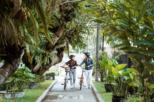 Dos asiático mujer caminando con plegable bicicleta mientras charlando —  Fotos de Stock