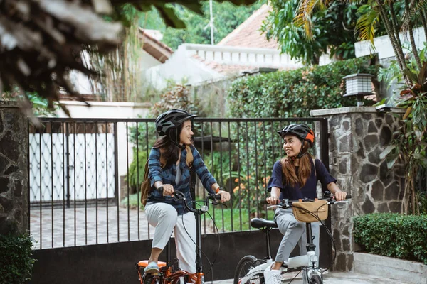 Dwie młode dziewczyny są gotowe iść do szkoły składając rower — Zdjęcie stockowe