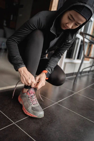 Jonge Aziatische moslim vrouwen dragen sport hijabs en repareren schoenveters aan de deur — Stockfoto