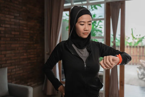 Hijab Sportliche asiatische Damen schauen auf das smarte Armband, um die Zeit zu bestimmen — Stockfoto