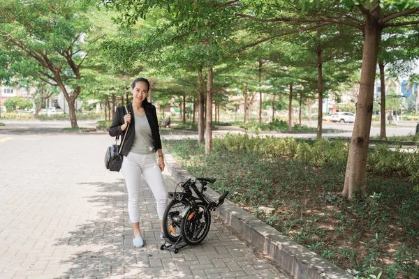 Mujer asiática joven trabajador de pie con su bicicleta plegable —  Fotos de Stock