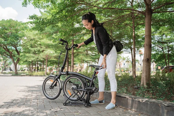 Mujer asiática tratando de doblar su bicicleta plegable — Foto de Stock