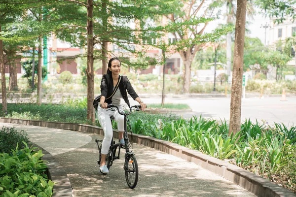 Femme d'affaires souriante chevauchant son vélo pliant — Photo