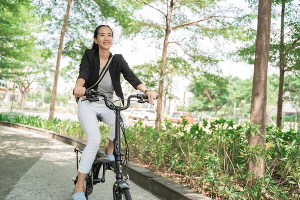 Femme d'affaires souriante chevauchant son vélo pliant — Photo