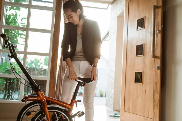 Asiático joven mujer de pie en sala de estar cuando abierto doblar su bicicleta plegable —  Fotos de Stock