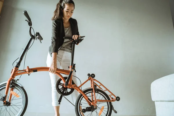 Asiático joven mujer de pie en sala de estar cuando abierto doblar su bicicleta plegable — Foto de Stock