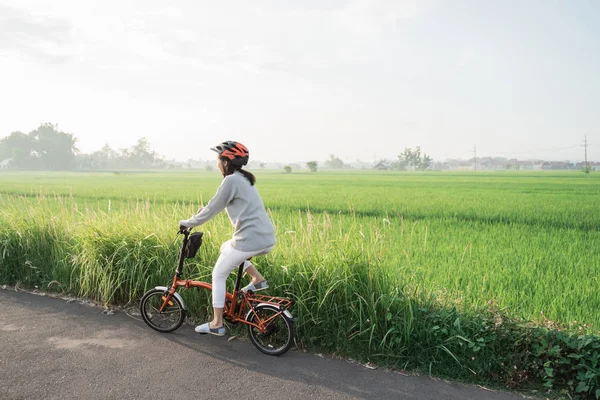 Azjatki noszą kaski do jazdy na składanych rowerach na polach ryżowych — Zdjęcie stockowe