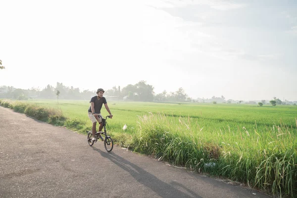 Junge Männer tragen Helme, um in Reisfeldern Klappräder zu fahren — Stockfoto
