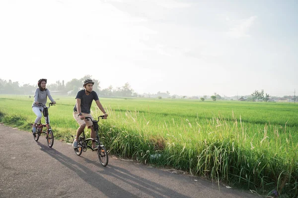 Młoda para nosić kaski do jazdy składane rowery w tle pól ryżowych — Zdjęcie stockowe