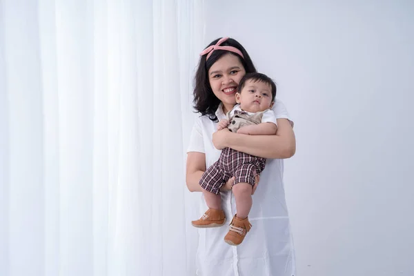 Lächelnde asiatische Mutter mit tragendem kleinen Sohn — Stockfoto
