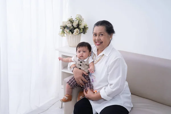 Nenek tersenyum duduk di sofa dengan anak kecil — Stok Foto