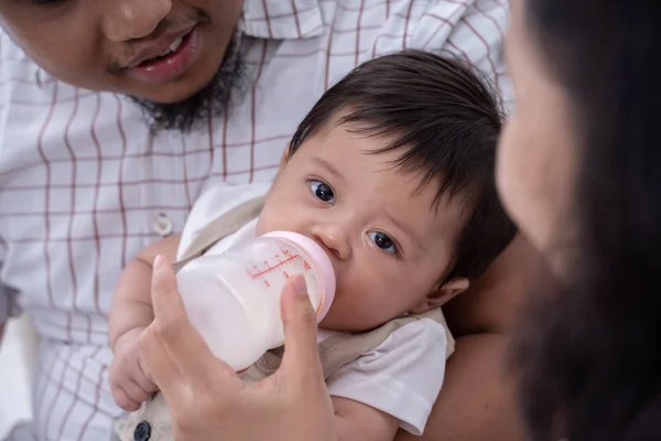 Aziatische moeder voeden zoon met melk in baby fles — Stockfoto