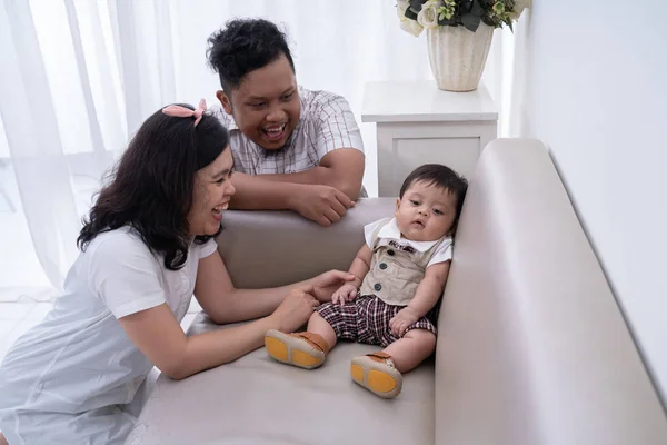 Senyum ayah dan ibu mencari dengan anak kecil duduk di sofa — Stok Foto