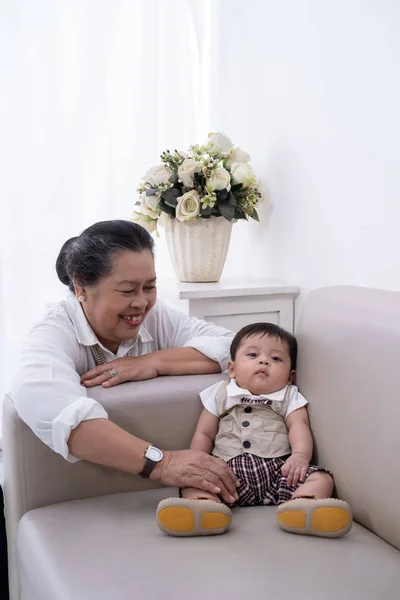 Schläfriger kleiner Junge sitzt auf dem Sofa bei seiner Großmutter — Stockfoto