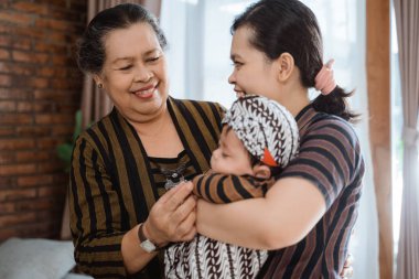 Uyuyan küçük oğlunu taşırken mutlu bir büyükanne ve anne.