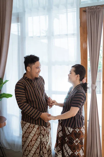 Feliz asiático casal sorrindo e segura as mãos vestindo javanês batik — Fotografia de Stock