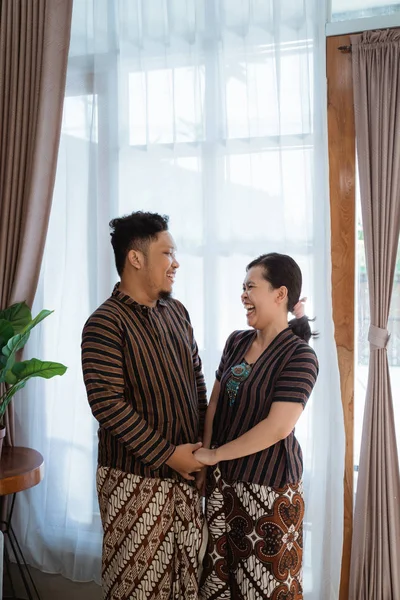 Avendo divertimento asiatico coppia sorridente e tiene le mani indossando javanese batik — Foto Stock
