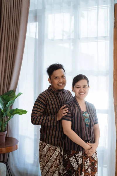 Pasangan asia yang romantis tersenyum dan berpose memeluk memakai batik javanese — Stok Foto