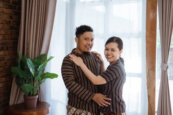 Asiático pareja sonriendo y abrazando pose usando javanese batik —  Fotos de Stock