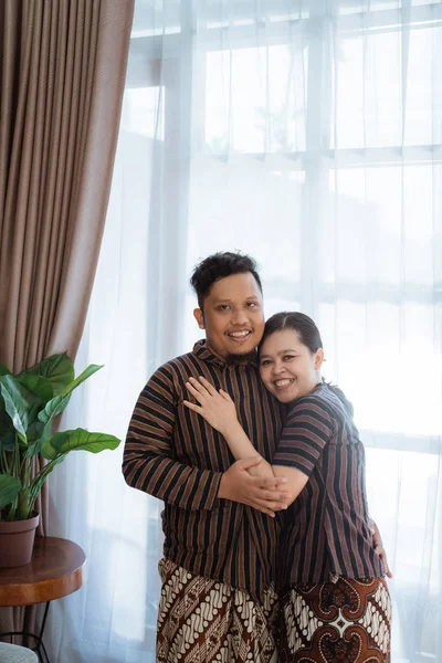 Pasangan asia yang romantis tersenyum dan berpose memeluk memakai batik javanese — Stok Foto