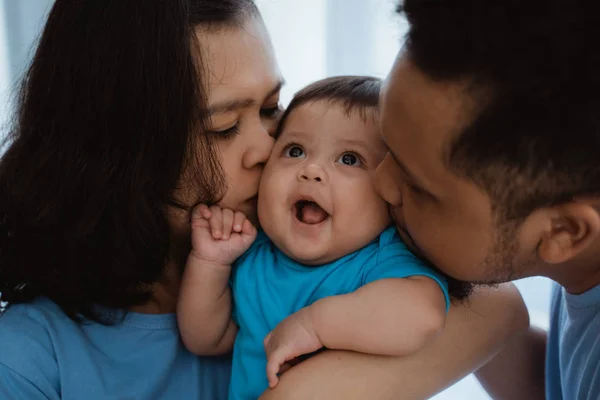 Niño sonríe cuando es besado por el padre y la madre — Foto de Stock