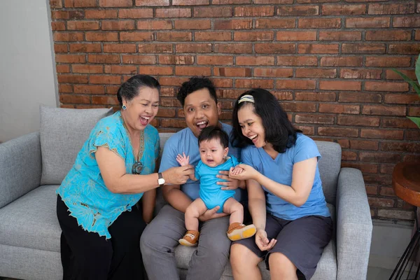 Pai mãe avó e neto sentado juntos no sofá enquanto brincava — Fotografia de Stock