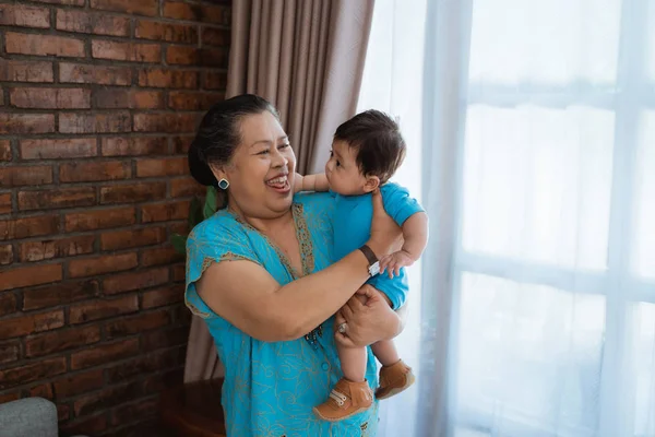 Lächelnde asiatische alte Frau steht mit tragendem kleinen Sohn — Stockfoto