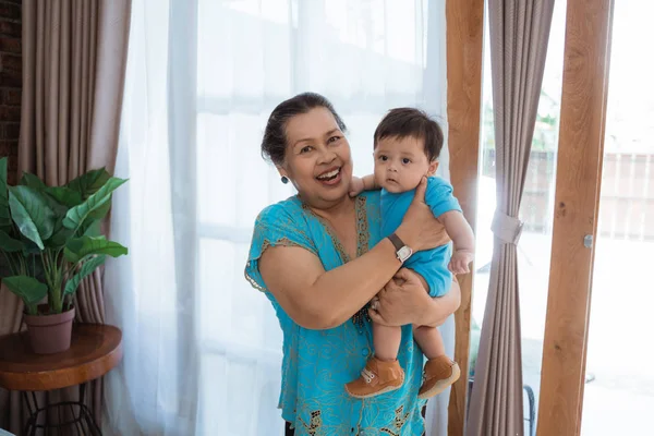 Oma staan met het dragen van kleine kleinzoon — Stockfoto