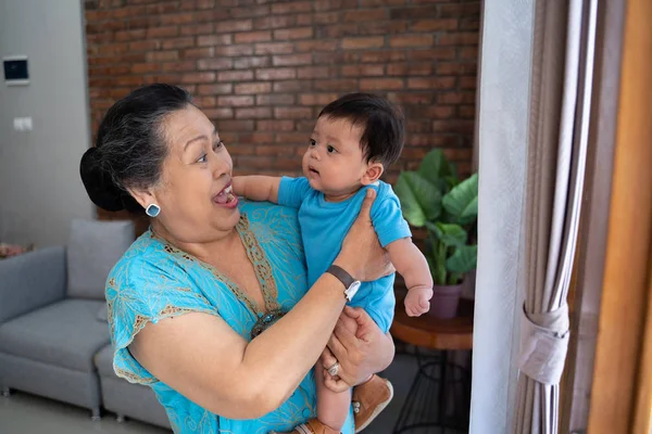 Sonriente asiático viejo mujer de pie con llevar poco hijo —  Fotos de Stock