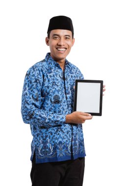 Batik Korpri giyen Asyalı genç adam tablet dijital kullanıyor.