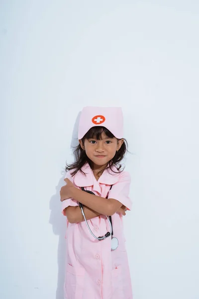Söt asiatisk liten flicka bär läkare uniform med händerna korsning — Stockfoto